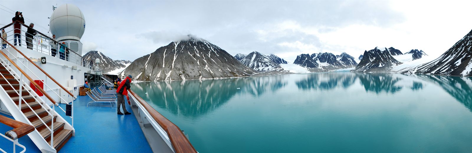 View from a ship’s deck over a still fjord